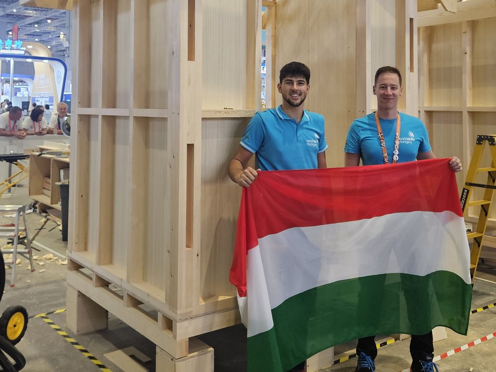 Two team members in front of the completed timber house